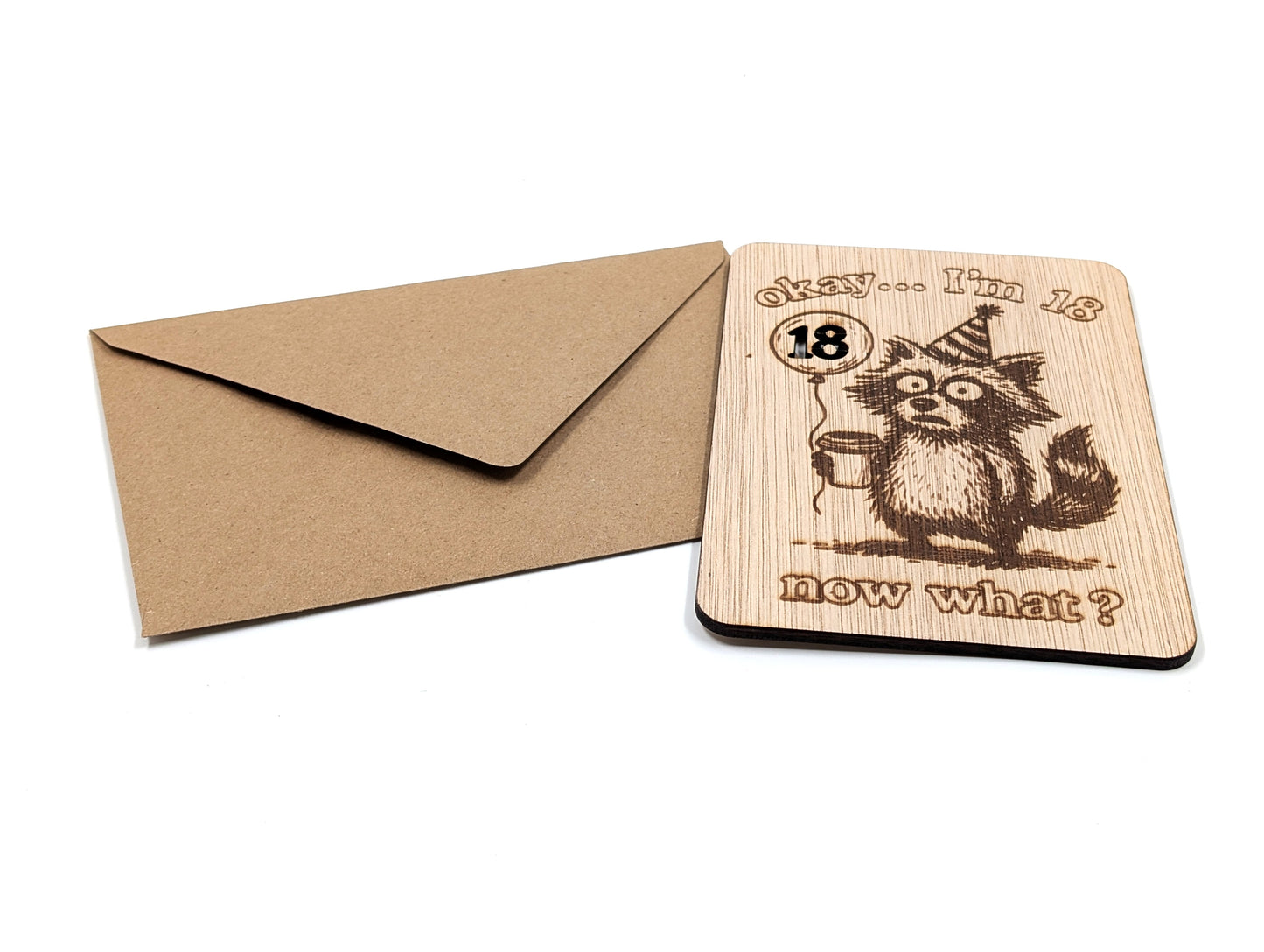 Handgemaakte houten wenskaart voor een 18e verjaardag naast een bruine kraft envelop op een witte ondergrond.